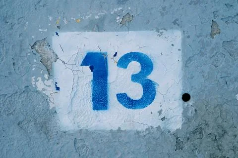 Number thirteen drawn in a white rectangle on a blue peeling wall Photos