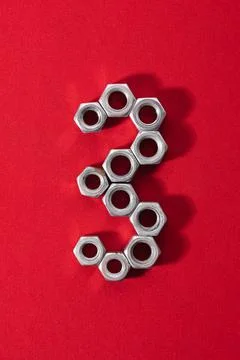 Number three, made with steel nuts on red fabric background Stock Photos