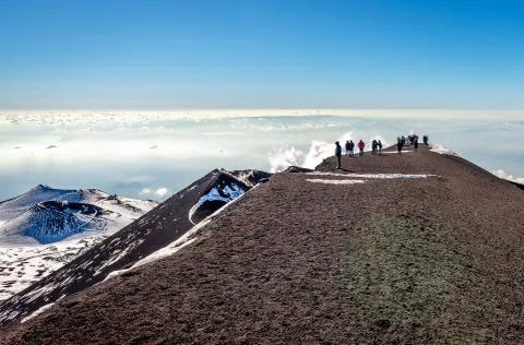 A number of unidentified hikers enjoy the view from Etna mountain. Stock Photos