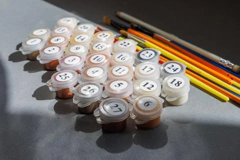 Numbered paint cans and brushes on a gray background. Painting by numbers. .. Stock Photos
