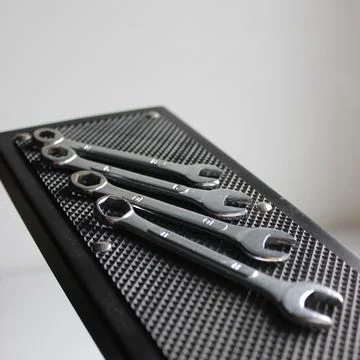 Numbered spanners on textured rubber surface of hanging shelf Stock Photos