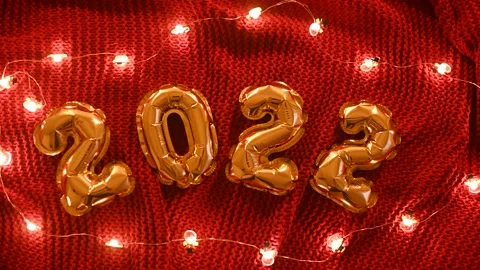 Numbers 2022 on the background of a red knitted cozy plaid and Christmas lights. Stock-Footage 166577116