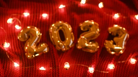 Numbers 2023 on the background of a red knitted cozy plaid and Christmas lights. Stock Footage 166576993