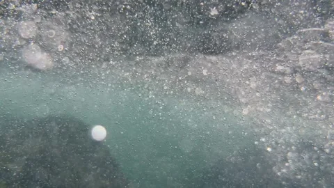 Numerous air bubbles fill the water after wave movement creating abstract motion Stock Footage 346246775