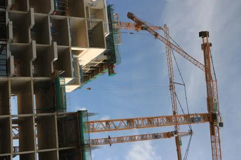 Numerous cranes for lifting materials on a construction site. Co Stock Photos
