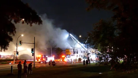 Numerous firefighters working on structure fire in the street Stock Footage 115968025