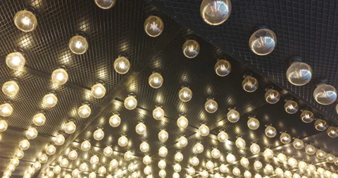 Numerous glowing light bulbs flicker rhythmically on a dark metal mesh ceil.. Stock Footage 332159087