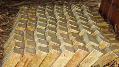 Numerous rectangular blocks of raw palm oil stacked in a repetitive pattern.. Foto stock