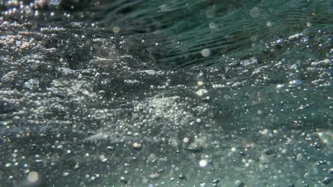 Numerous underwater air bubbles and tiny particles drift through seawater Stock Footage 335276875