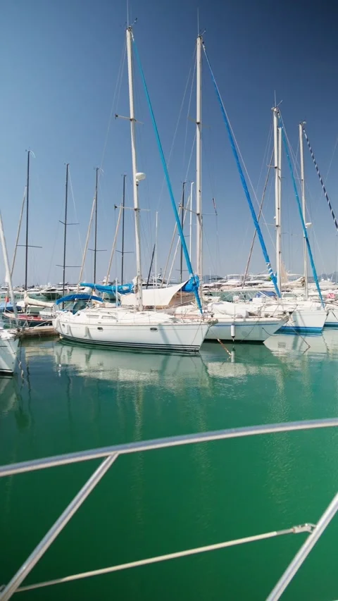 Numerous white sailing yachts moored in a tranquil marina with calm, emerald Stock-Footage 337419540