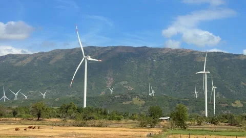 Numerous wind turbines operate along rolling hills, rotating in unison with 库存影片 329373341