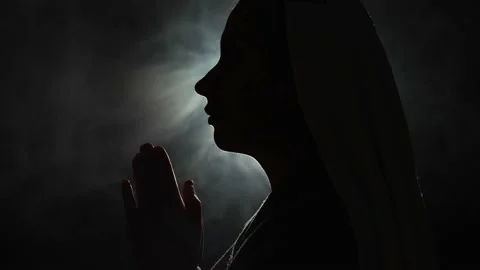 Nun praying in a dark place Stock Footage 176880337