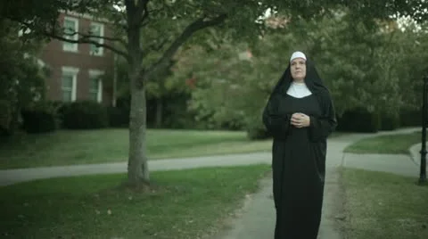 Nun walking down sidewalk side walk Stock Footage