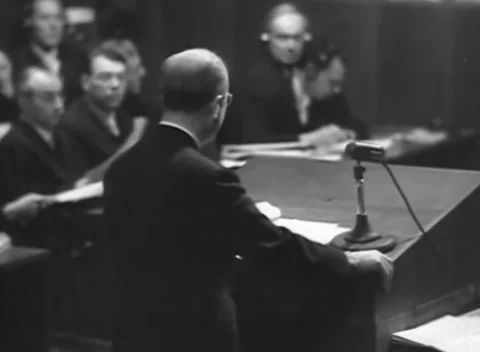 NUREMBERG - 1945: Counsel reading - Speaker leans over open document Stock Footage 344489852