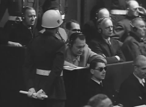 NUREMBERG - 1945: Dock paperwork - Defendant studies papers under guard Stock Footage 344489878