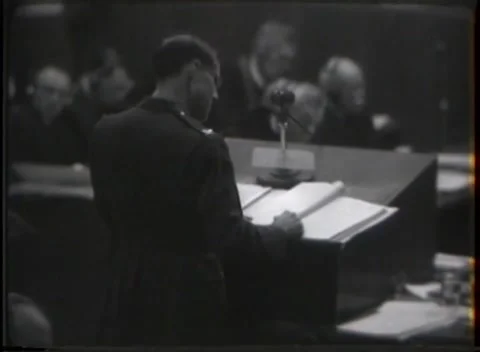 NUREMBERG - 1946: Uniformed man reads at a courtroom stand Stock Footage 342920982