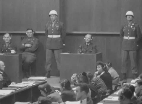 NUREMBERG, GERMANY - 1946: Box vigil - Headphoned witness sits between policemen Stock Footage 344490388
