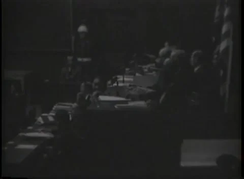 NUREMBERG, GERMANY - 1946: Desk blotter - Tribunal confers beneath hanging flag Stock Footage 344901465