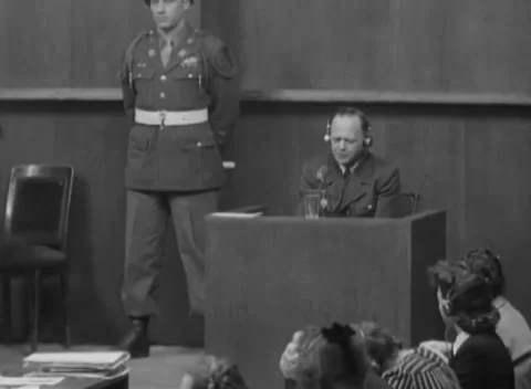 NUREMBERG, GERMANY - 1946: Downcast study - Witness looks down beside guard Stock Footage 344490298