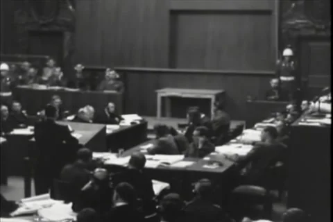 NUREMBERG, GERMANY - 1946: Headset workforce - Rows study papers near guard Stock Footage 344489484