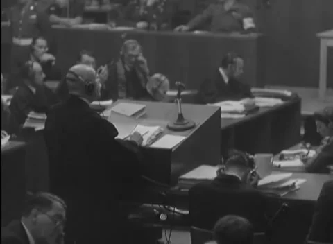 NUREMBERG, GERMANY - 1946: Held document - Headset wearer steadies paper on desk 動画素材 344490992