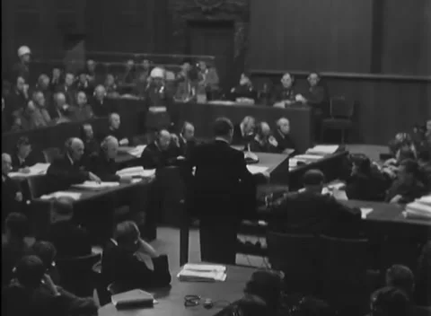 NUREMBERG, GERMANY - 1946: Left-table notes - Lawyers consult files under guard Stock Footage 344489426
