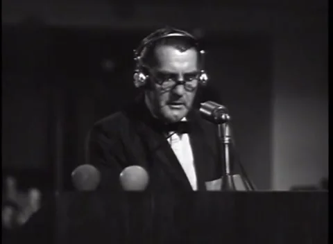 NUREMBERG, GERMANY - 1946: Outlined ear cups - Speaker raises his head to talk 動画素材 344901606