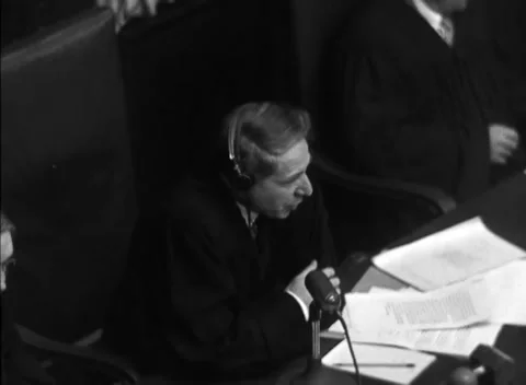 NUREMBERG, GERMANY - 1947: Arraignment — Judge speaks over fanned documents Stockbeeldmateriaal 343320792