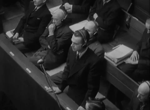 NUREMBERG, GERMANY - 1947: Hand to face - Headphoned men sit beside bound file Stock Footage 344489032