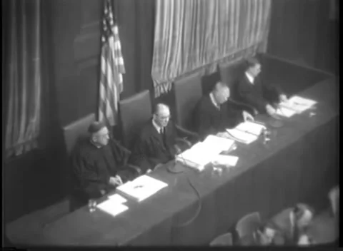 NUREMBERG, GERMANY - 1947: Paper stack - Judge leans across tribunal bench Stock Footage 344489132