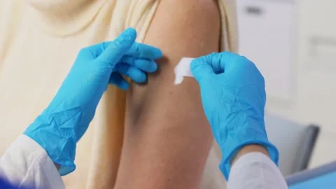 Nurse applying medical patch to vaccinated woman Stock Footage 168672564