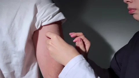 Nurse applying a sticking plaster on a man's arm after a vaccination, wound Stock Footage 222883343