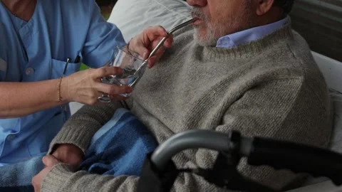 Nurse assisting elderly man drinking water with straw Stock Footage 300171999