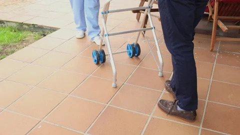 Nurse assisting elderly man learning to walk with walker Stock Footage 300171915