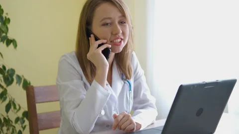 A nurse in a bathrobe and with a stethoscope is talking on a smartphone behind a Stock Footage 177881079