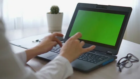 A nurse in a bathrobe is typing on a laptop with a green screen on the table Stock-Footage 177883053