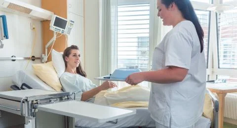 Nurse bringing woman patient meal on the hospital bed Stock Photos