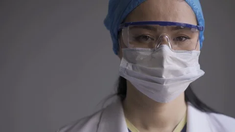 Nurse carefully looking at camera wearing a medical uniform, a protective mask Stock Footage 130133749