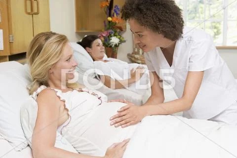 Nurse checking pregnant woman's belly and smiling Stock-Fotos