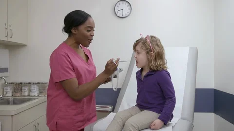 Nurse checks temperature of a pediatric patient in exam room Stock Footage