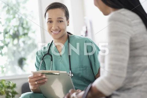 Nurse With Clipboard Sitting With Patient