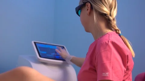 Nurse does laser hair removal on girl leg surfing internet Stock-Footage 104087341