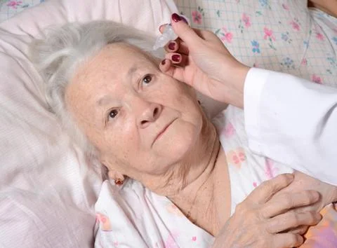 Nurse dripping eye drops to old woman 写真素材