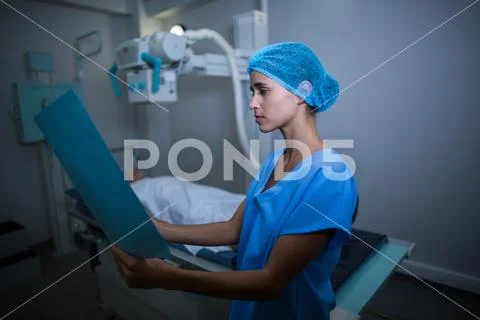 Nurse examining medical report in x-ray room Stock Photos