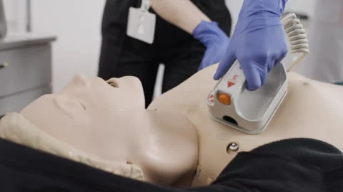 Nurse at a first aid course with defibrillator demonstrates work on a dummy Video stock 270169885