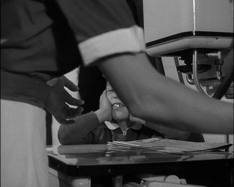 Nurse folding objects from newspaper for young boy sitting next to her, 1952 Stock Footage 133375944