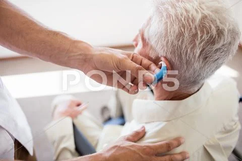 Nurse Giving Hearing Device To A Senior Man