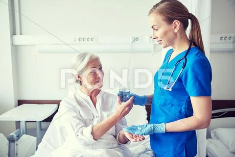 Nurse giving medicine to senior woman at hospital Stock Photos