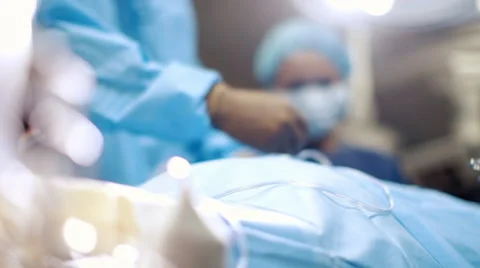 Nurse handing forceps to surgeon in operating room Видео 67178142