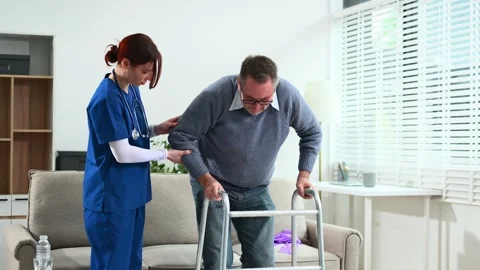 Nurse helps elderly man stand with walker during a home care session. Conce.. Video stock 316458736